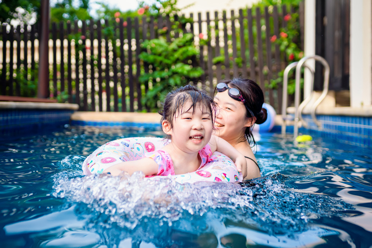 Happy asian girl with her mother having fun in the swimming pool - Cute girl with her mother playing in swimming pool during summer