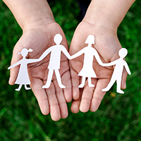 hands holding a paper cutout of children